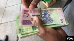 FILE: A man in Harare holds bondnotes issued by Reserve Bank of Zimbabwe, Oct. 15, 2018. The introduction of bond notes - a currency Zimbabwe started printing two years ago to ease the situation -- has not helped. (C.Mavhunga/VOA)
