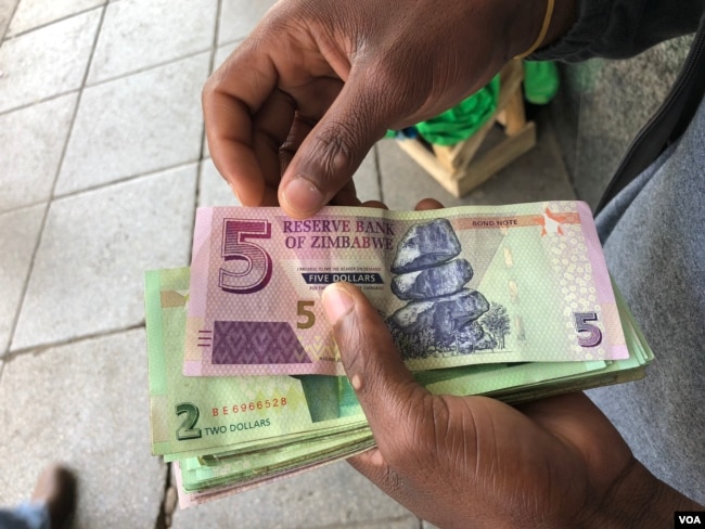A man in Harare holds bond notes issued by Reserve Bank of Zimbabwe, Oct. 15, 2018. The introduction of bond notes - a currency Zimbabwe started printing two years ago to ease the situation -- has not helped. (C.Mavhunga/VOA)