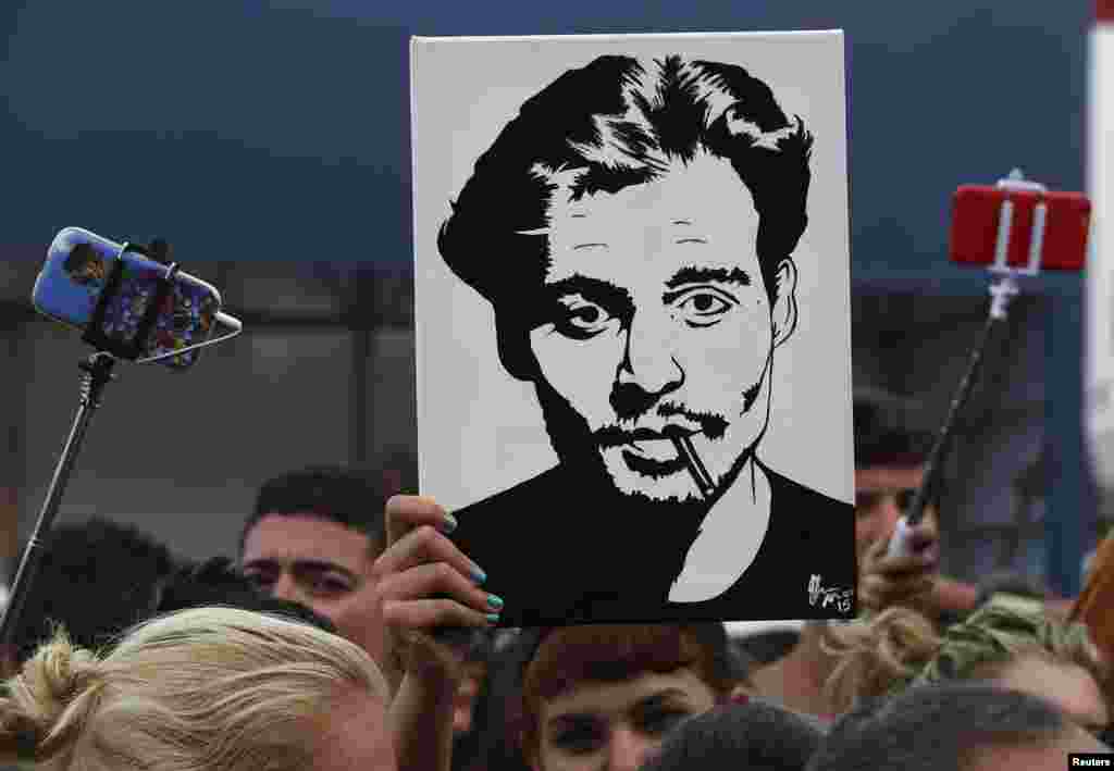 A girl (C) holds up a portrait of actor Johnny Depp in front of the entrance of the venue of the 72nd Venice Film Festival, northern Italy. Depp attended the red carpet event for the movie "Black Mass."