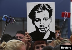 A girl (C) holds up a portrait of actor Johnny Depp in front of the entrance of the venue of the 72nd Venice Film Festival, Sept. 4, 2015.
