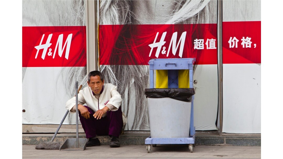 Petugas kebersihan duduk di depan toko H&M di Guangzhou, Provinsi Guangdong, 26 Februari 2014. (Foto: REUTERS/Alex Lee)