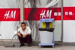 Petugas kebersihan duduk di depan toko H&M di Guangzhou, Provinsi Guangdong, 26 Februari 2014. (Foto: REUTERS/Alex Lee)