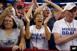 FILE - Supporters of President Donald Trump, wearing Mike Braun for Congress shirts, cheer as he arrives for a campaign rally at the Ford Center in Evansville, Ind., Aug. 30, 2018.