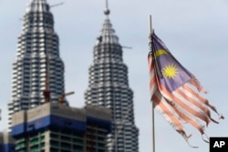 Bendera nasional Malaysia yang rusak terlihat berkibar di depan Menara Petronas di Kuala Lumpur, Malaysia. (Foto: AP)
