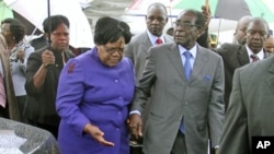 FILE: Zimbabwean President Robert Mugabe (R) is greeted by Vice President Joice Mujuru (L) after a trip to Singapore that had ignited speculation the veteran leader was seriously ill, as he returns home to Harare, Zimbabwe, April 12, 2012.