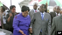 FILE: Zimbabwean President Robert Mugabe (R) is greeted by Vice President Joice Mujuru (L) after a trip to Singapore that had ignited speculation the veteran leader was seriously ill, as he returns home to Harare, Zimbabwe, April 12, 2012.