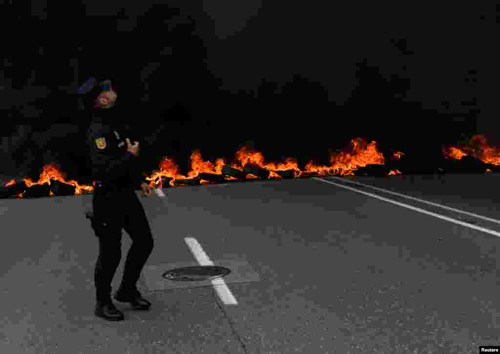 A member of riot police walks in front of a flaming barricade during a May Day rally in Gijon, Spain.