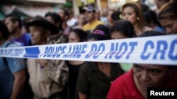 People stand behind a police line at a crime scene in Tegucigalpa, Honduras, Nov. 19, 2013.