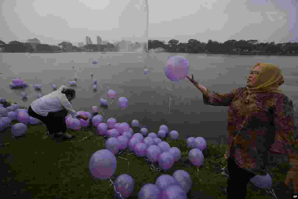 Para perempuan melepaskan balon sebagai simbol doa mereka bagi ke-239 penumpang pesawat MH370, di sebuah taman di Kuala Lumpur, 30 Maret 2014.