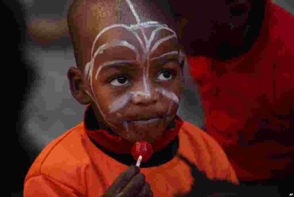 A child from the nearby poverty-stricken Alexandra Township eats a lollipop on a visit to Mandela Square in Sandton, Johannesburg, Friday, July 18, 2014.