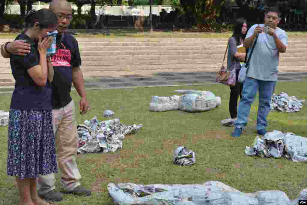 Slain reporter&#39;s wife Edita Tiamzon and National Union of Journalists of the Philippines Director Nonoy Espina circle an exhibit depicting fallen victims of the Maguindanao massacre, in Quezon City. (Simone Orendain/VOA)