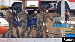 Soldados cargan el cuerpo de una víctima del naufragio frente a Lampedusa.