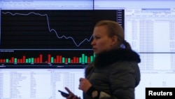 Seorang warga Rusia melewati layar monitor informasi bursa saham di gedung Moscow Stock Exchange di Moskow, Rusia (foto: ilustrasi). 