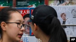 两位女子在展示中国领导人习近平和青春偶像鹿晗的杂志的一处北京报摊前聊天。（2017年10月22日）