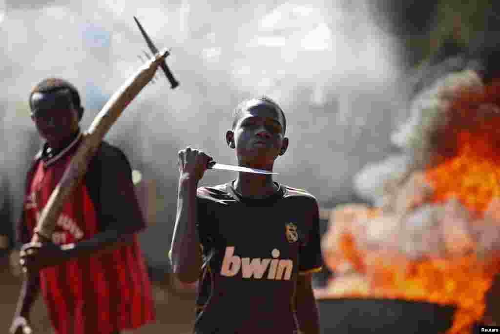 A boy gestures with a knife in front of a barricade that is on fire during a protest after French troops opened fire on protesters blocking a road in Bambari, Central African Republic.