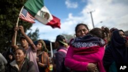 La migrante hondureña Leticia Nunes sostiene a su hija Mailyn junto a un pequeño grupo de migrantes que intentaron pasar el cruce fronterizo de Chaparral en Tijuana, México, el jueves 22 de noviembre de 2018.