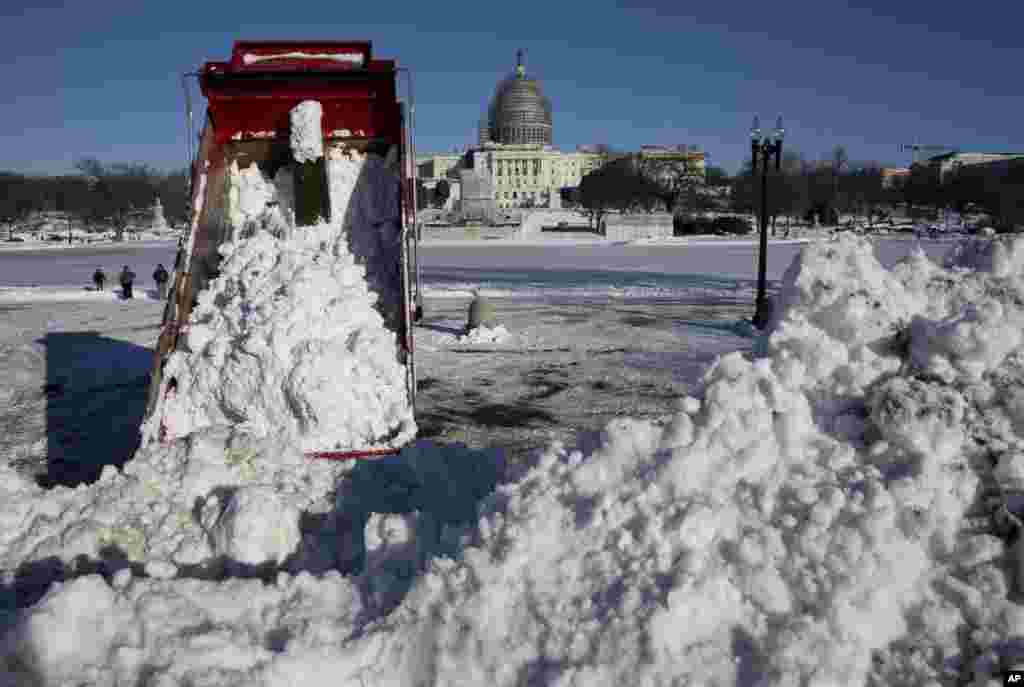 Truk pengeruk salju membuang salju dekat Gedung DPR AS di Washington, 24 Januari 2016. Washington membersihkan salju yang turun dalam badai salju dahsyat yang membuat kawasan pesisir timur AS lumpuh.