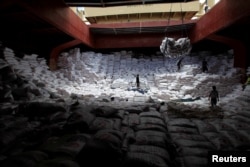 Workers unload sacks of rice from a Vietnam cargo ship carrying some 12, 700 tonnes of rice, at the port in Manila July 5, 2014.