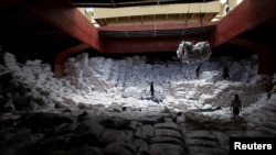 FILE - Workers unload sacks of rice from a Vietnam cargo ship carrying some 12, 700 tonnes of rice, at the port in Manila July 5, 2014.