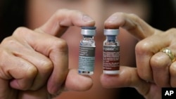 A Manila Health officer shows off a pair of vials of the anti-dengue vaccine Dengvaxia after being recalled from local government health centers Tuesday, Dec. 5, 2017 in Manila, Philippines. The World Health Organization says the first-ever vaccine for dengue needs to be dealt with in "a much safer way," meaning that the shot should mostly be given to people who have previously been infected with the disease.