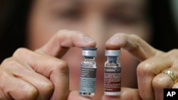 A Manila Health officer shows off a pair of vials of the anti-dengue vaccine Dengvaxia after being recalled from local government health centers Tuesday, Dec. 5, 2017 in Manila, Philippines. The World Health Organization says the first-ever vaccine for de