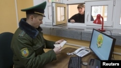 FILE - A Belarussian border guard checks a tourist's passport at a border crossing with Poland, near the village of Pererov, southwest of Minsk, March 31, 2015.