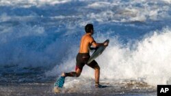 A bodeyboarder runs into the waves at Waimea Bay after the Memory of Eddie Aikau surfing contest was canceled, Feb. 10, 2016, in Haleiwa, Hawaii. 