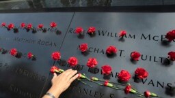Norma Molina, de San Antonio, Texas, coloca flores en los nombres de bomberos en el Memorial del 11 de septiembre en la ciudad de Nueva York el 9 de septiembre, de 2019.