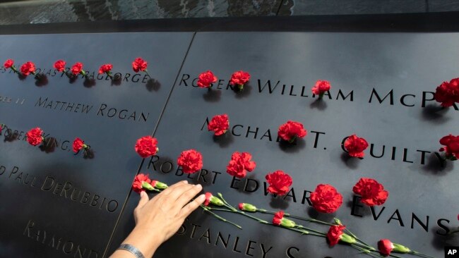 一名美国女子在纽约911纪念园地为她在2001年911恐袭中丧生的男友献上鲜花。（2019年9月9日）