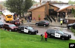 FILE - Police and others are seen outside a recreation center where students are reunited with their parents, in the Denver suburb of Highlands Ranch, Colo., after a shooting at STEM School Highlands Ranch, May 7, 2019.