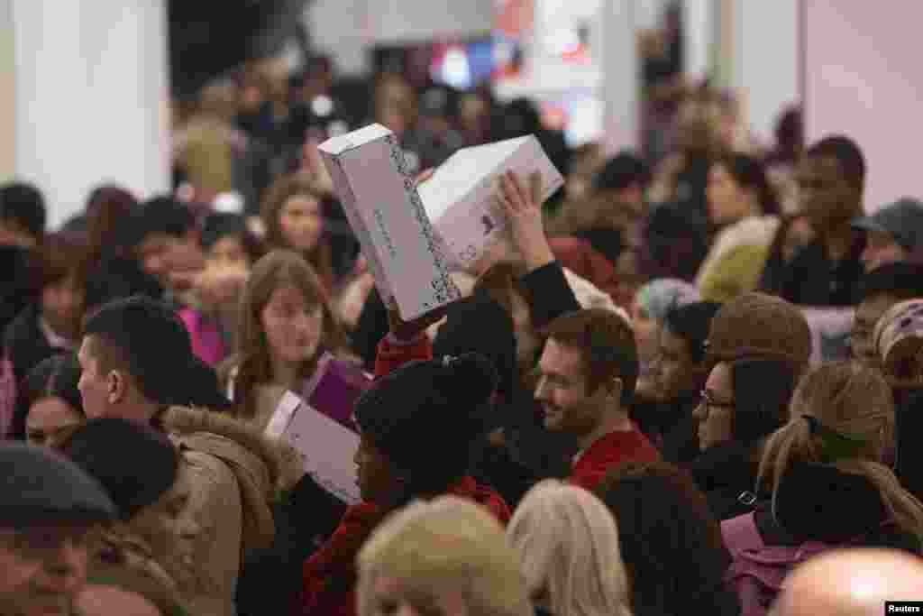 People carry shoes in Macy's during Black Friday sales in New York, Nov. 27, 2014.
