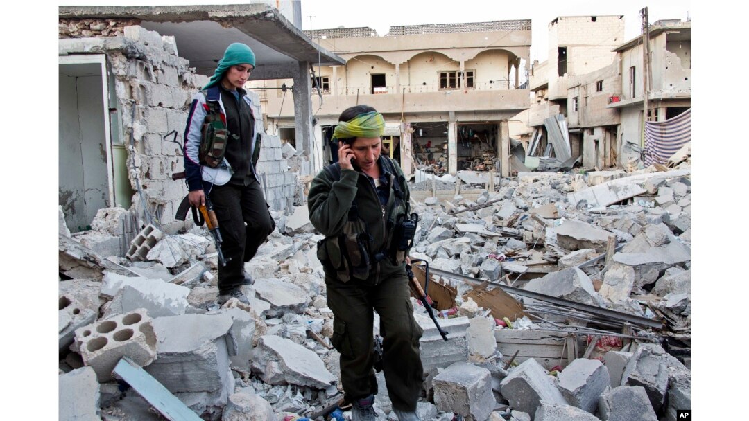 FILE - Kurdish female fighters move to another secured point in the contested zone of Kobani, Syria, on Nov. 19, 2014.