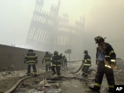 FILE - With the skeleton of the World Trade Center twin towers in the background, New York City firefighters work amid debris on Cortlandt Street after the terrorist attacks, Sept. 11, 2001.