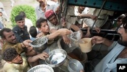 Pakistani men and boys gather to receive food at a camp for the displaced set up inside a college on the outskirts of Nowshera, 2 August 2010