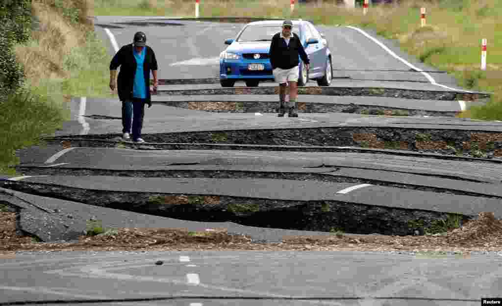 Local residents Chris and Viv Young look at damage caused by an earthquake, along State Highway One near the town of Ward, south of Blenheim on New Zealand&#39;s South Island.