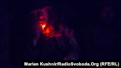 Михайло курить у суцільній темряві бліндажа під час спостереження на передових позиціях