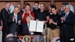 President Donald Trump, accompanied by coal miners and cabinet members holds up the signed Energy Independence Executive Order, on March 28, 2017. (AP Photo/Pablo Martinez Monsivais) 