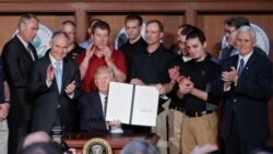 President Donald Trump, accompanied by coal miners and, from left, Interior Secretary Ryan Zinke, EPA Administrator Scott Pruitt, second from right, Energy Secretary Rick Perry, and Vice President Mike Pence, far right, holds up the signed Energy Independ