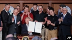 President Donald Trump, accompanied by coal miners and, from left, Interior Secretary Ryan Zinke, EPA Administrator Scott Pruitt, second from right, Energy Secretary Rick Perry, and Vice President Mike Pence, far right, holds up the signed Energy Independence Executive Order, March 28, 2017. 
