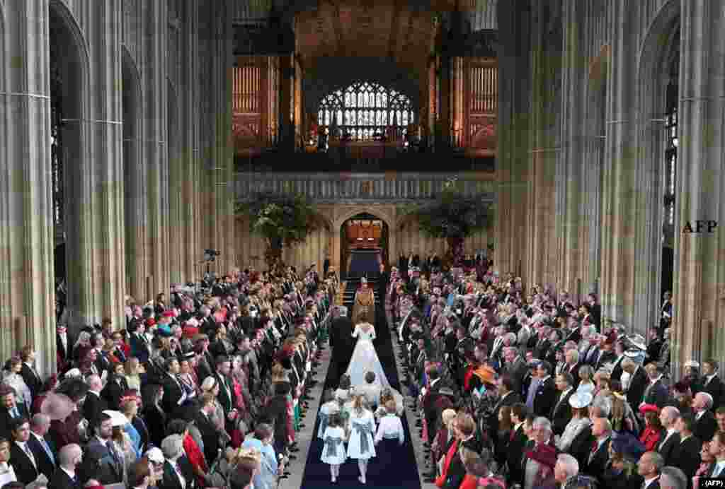 2018年10月12日，英国女王伊丽莎白二世的孙女尤金妮公主在婚礼中，在父亲的伴随下走在温莎城堡的圣乔治教堂里。
