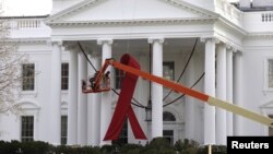 A large red ribbon is installed on the North Portico of the White House to mark World AIDS Day on December 1, in Washington, D.C., November 30, 2012.