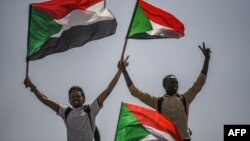 Sudanese protesters flash the victory sign and wave national flags during a rally outside the army headquarters in the capital, Khartoum, April 19, 2019.