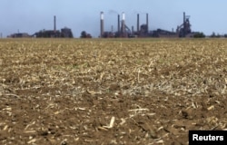 FILE - Chimneys from ArcelorMittal steel company are seen behind a dry maize field near Vanderbijlpark outside Johannesburg, Oct. 1, 2015.