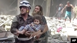 In this image made from video and posted online from Validated UGC, a Civil Defense worker carries a child after airstrikes hit Aleppo, Syria, April 28, 2016. 
