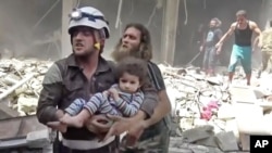 In this image made from video and posted online from Validated UGC, a Civil Defense worker carries a child after airstrikes hit Aleppo, Syria, April 28, 2016.
