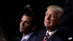 FILE - Republican Presidential Candidate Donald Trump and his son Donald Trump Jr., watch as Eric Trump addresses the delegates during the third day session of the Republican National Convention in Cleveland, July 20, 2016.
