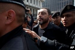 FILE - Guatemala's former Interior Minister, Mauricio Lopez Bonilla, is escorted by police as he arrives to a court in Guatemala City, June 11, 2016.