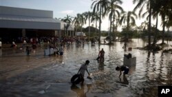 Warga berupaya mencari barang-barang berharga di areal parkir di sekitar toko, selatan Acapulco, di Punta Diamante, Meksiko, melalui air banjir yang masih setinggi pinggang, Rabu (18/9).