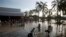 People wade through waist-high water in a store's parking, looking for valuables, south of Acapulco, in Punta Diamante, Mexico, Sept. 18, 2013. 