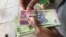 A man in Harare holds bondnotes issued by Reserve Bank of Zimbabwe, Oct. 15, 2018. The introduction of bond notes - a currency Zimbabwe started printing two years ago to ease the situation -- has not helped. (C.Mavhunga/VOA)